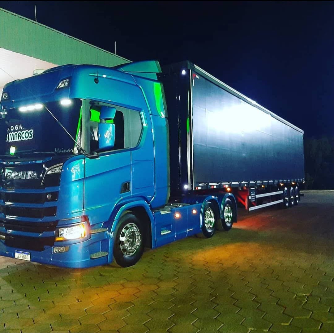 Scania azul com carreta sider à noite